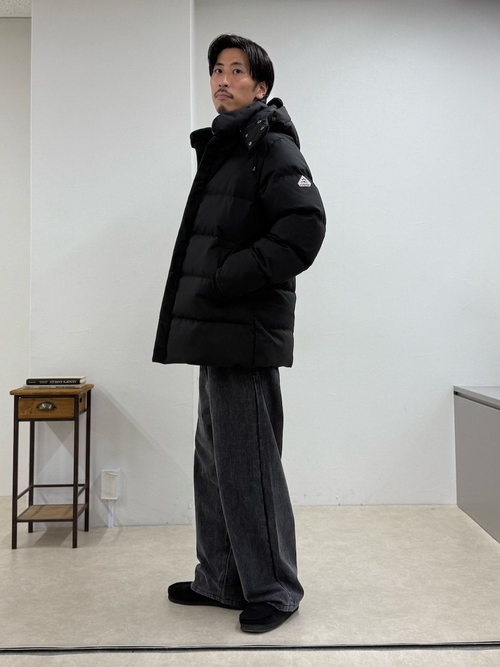 ブラック系のダウンジャケット/コート、ベージュ系のニット/セーター、グレー系のその他パンツを着用したメンズの秋コーディネートの2枚目の写真