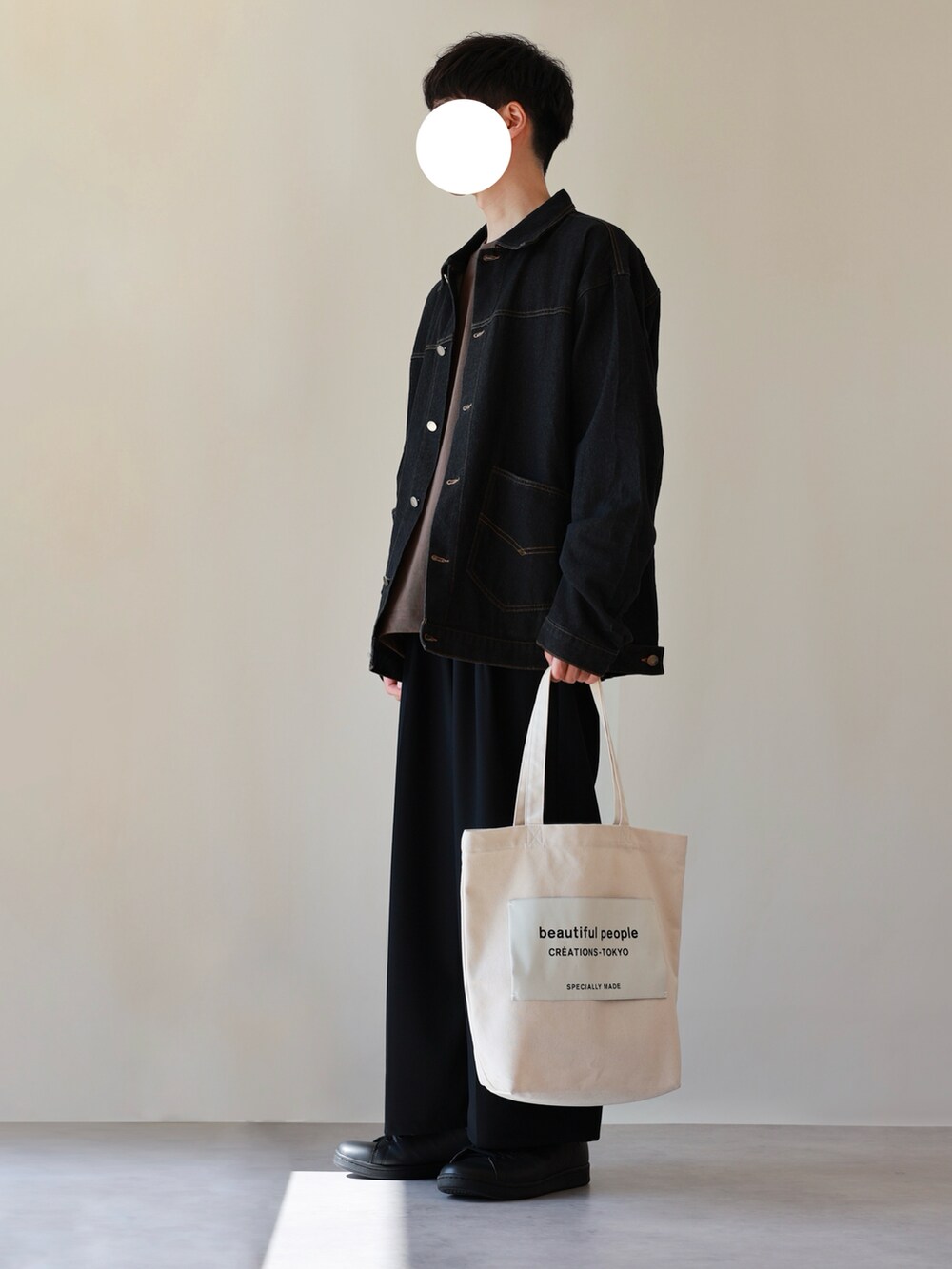 ホワイト系のトートバッグ、ブラック系のスニーカー、ブラック系のスラックスを着用したメンズの秋コーディネートの2枚目の写真