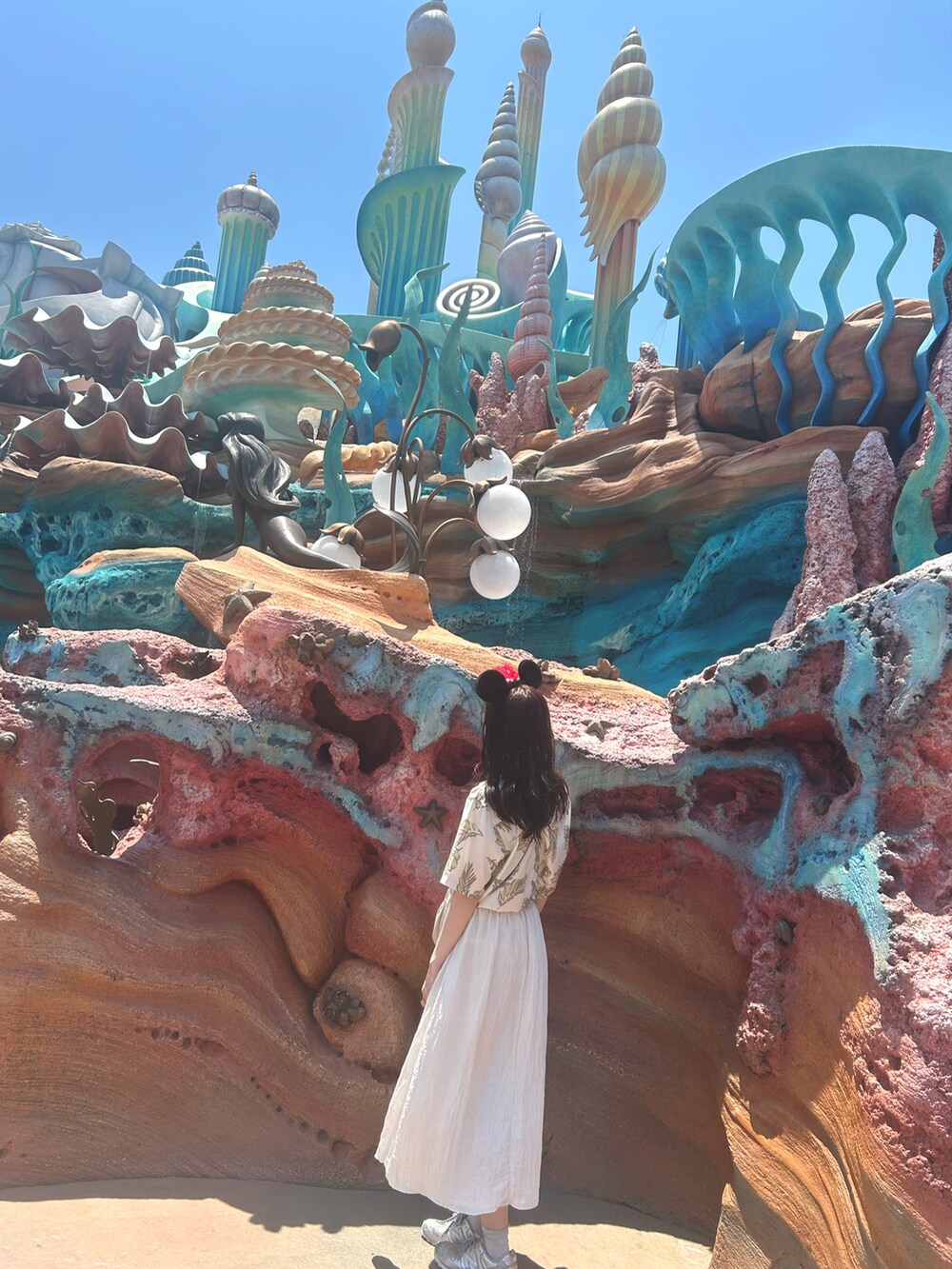 シルバー系のスニーカー、ホワイト系のシャツ/ブラウス、ベージュ系のショルダーバッグを着用したレディースの夏コーディネートの2枚目の写真