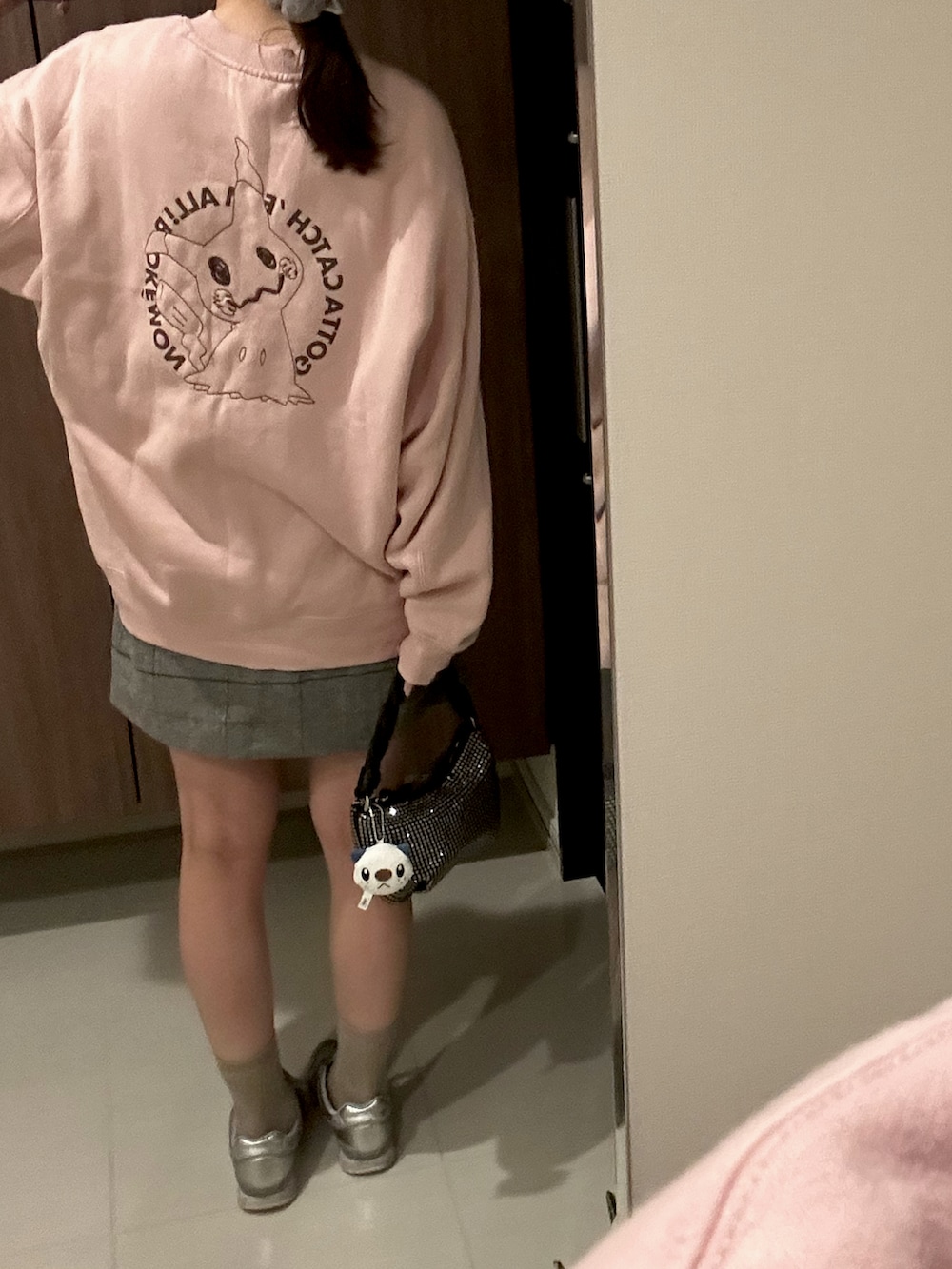 ブラック系のハンドバッグ、ピンク系のスウェット、シルバー系のスニーカーを着用したレディースの秋コーディネートの2枚目の写真