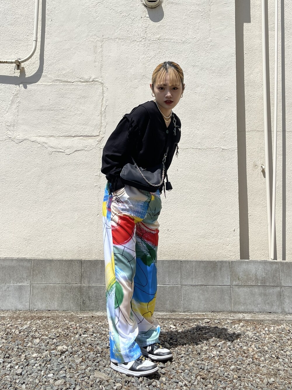 ホワイト系のスラックス、ブラック系のスニーカー、ブラック系のバッグを着用したレディースの冬コーディネートの2枚目の写真