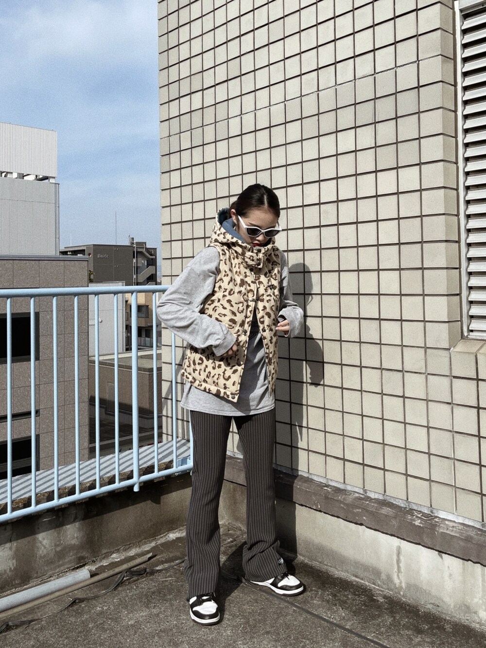 ブラック系のスニーカー、ベージュ系のダウンベスト、グレー系のその他パンツを着用したレディースの秋コーディネートの2枚目の写真