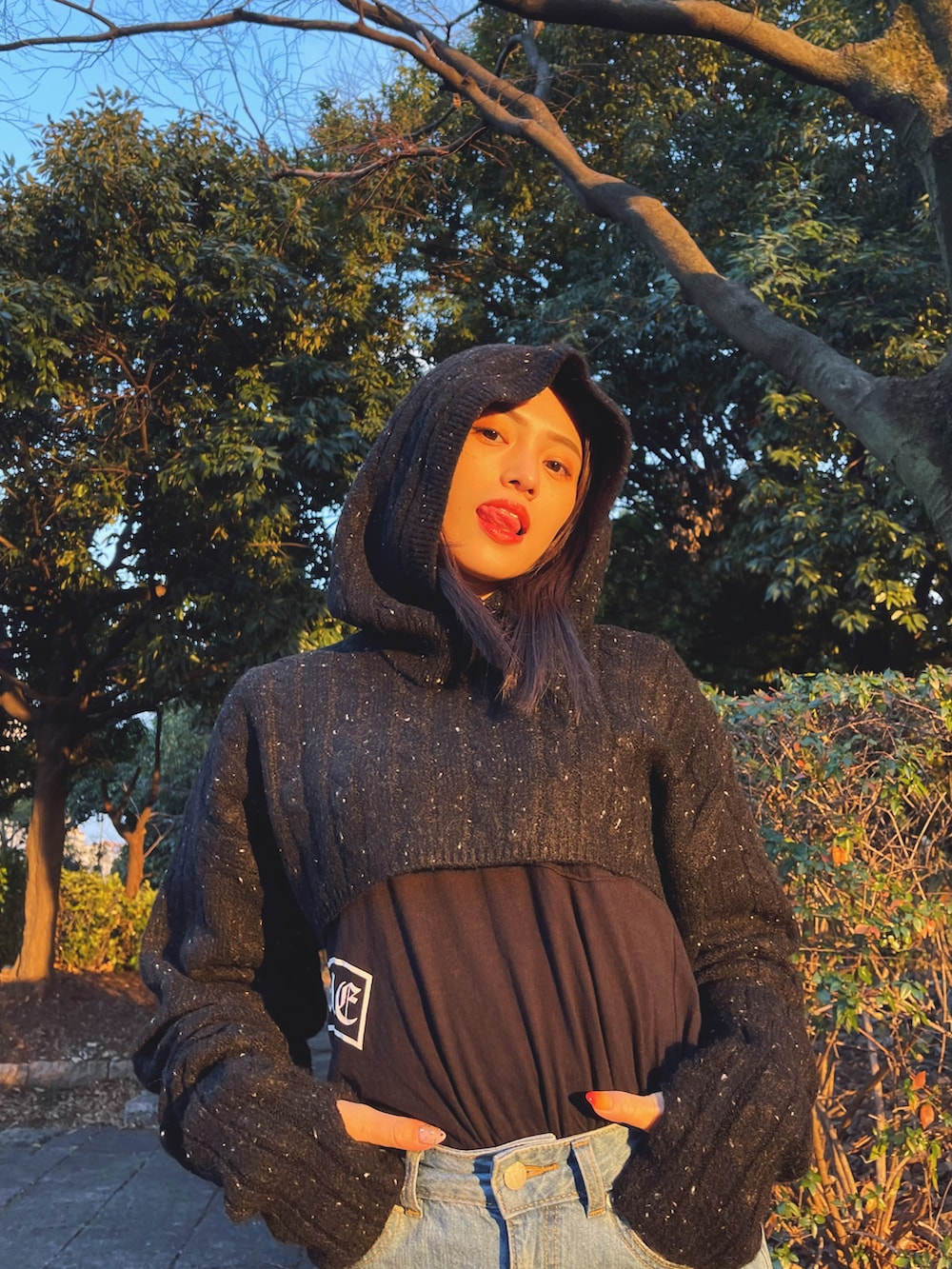 ブラック系のニット/セーター、ブラック系のTシャツ/カットソー、ブルー系のデニムスカートを着用したレディースの冬コーディネートの2枚目の写真