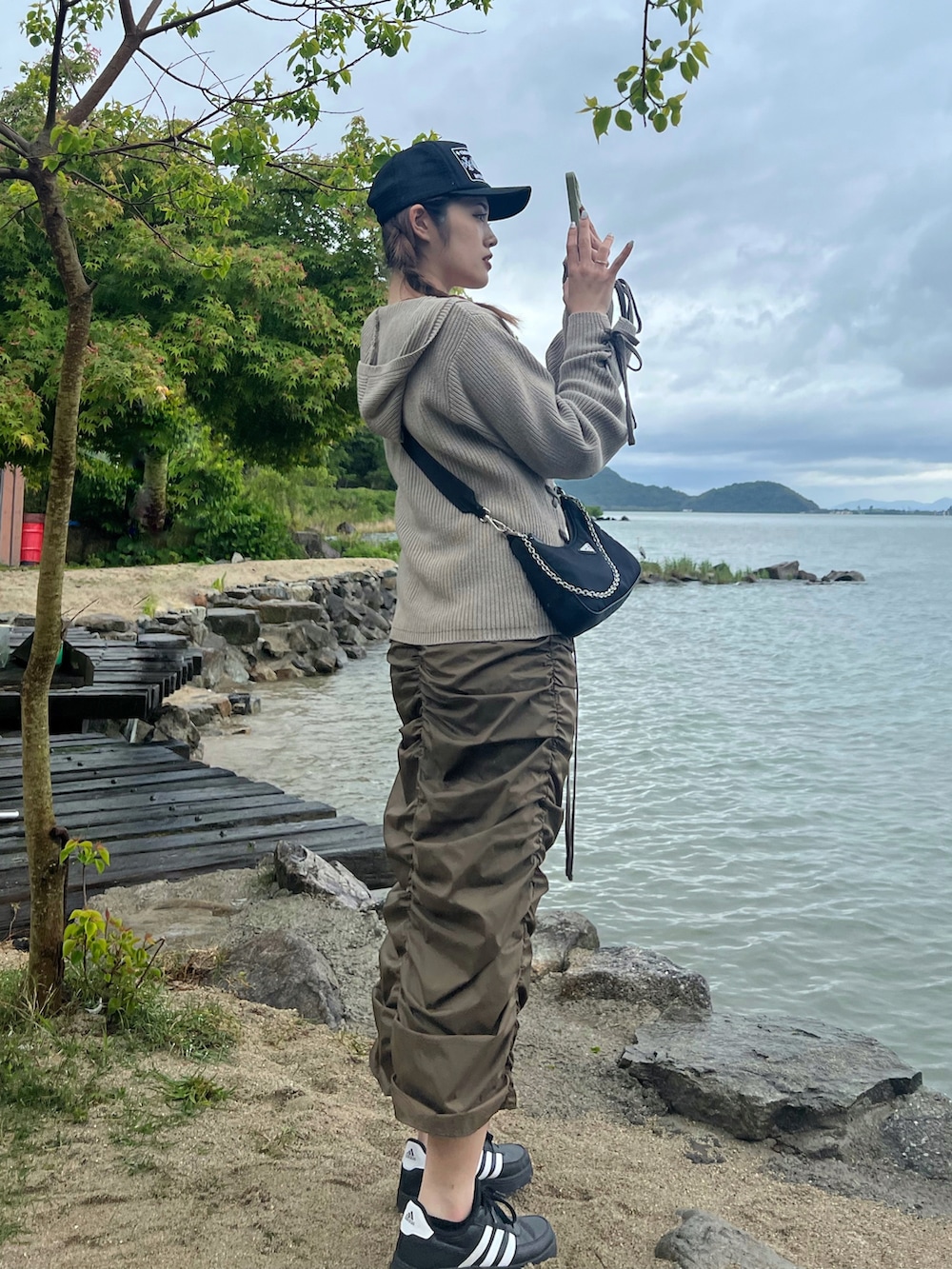 グリーン系のスカート、ブラック系のスニーカー、ベージュ系のカーディガン/ボレロを着用したレディースの春コーディネートの2枚目の写真