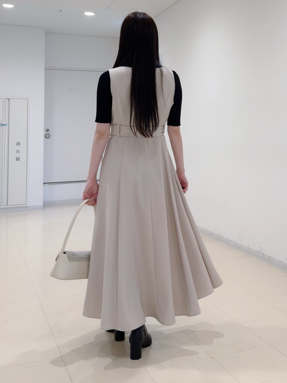 ブラック系のニット/セーター、ベージュ系のワンピース、ブラック系のブーツを着用したレディースの春コーディネートの4枚目の写真