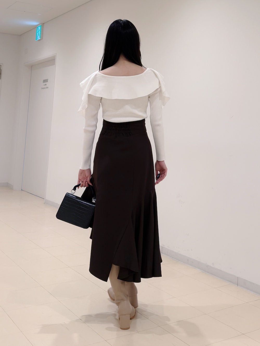 ホワイト系のニット/セーター、ブラウン系のスカート、ブラック系のハンドバッグを着用したレディースの秋コーディネートの3枚目の写真
