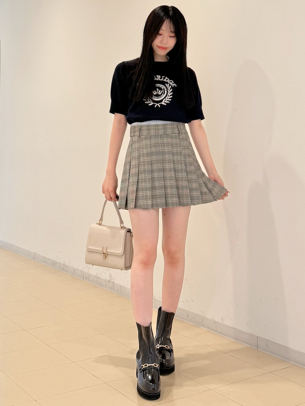 ブルー系のニット/セーター、グレー系のスカート、ホワイト系のハンドバッグを着用したレディースの夏コーディネートの2枚目の写真