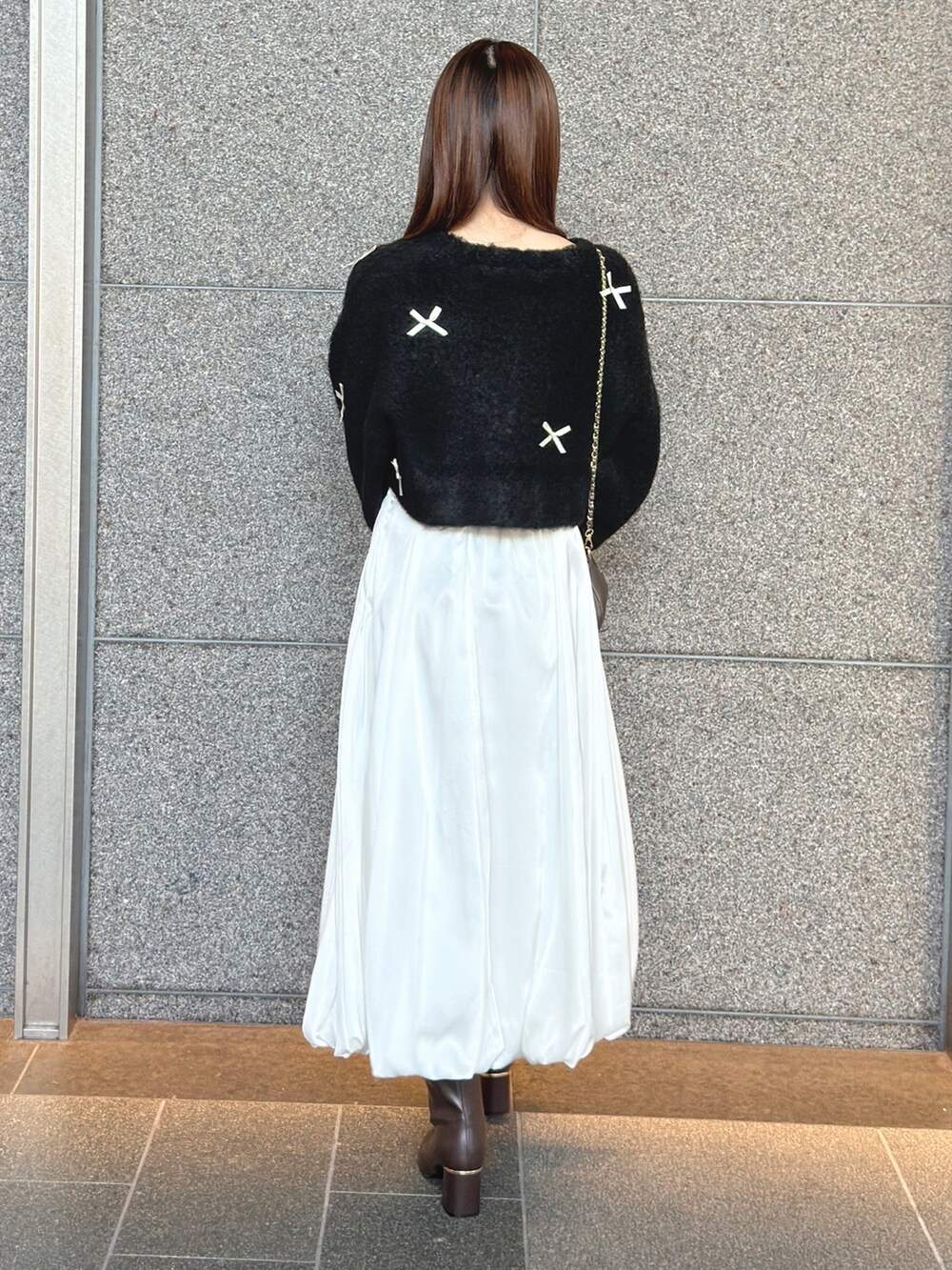 ブラック系のカーディガン/ボレロ、ホワイト系のスカート、ブラウン系のハンドバッグを着用したレディースの秋コーディネートの5枚目の写真