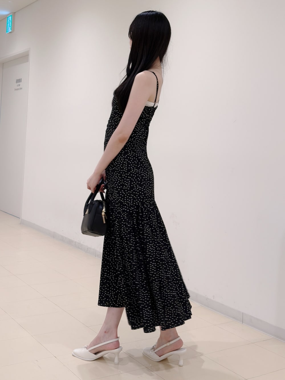 ブラック系のワンピース、ブラック系のハンドバッグ、ホワイト系のパンプスを着用したレディースの秋コーディネートの3枚目の写真