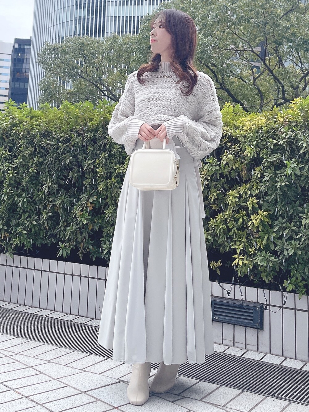 グレー系のニット/セーター、グリーン系のスカート、ホワイト系のハンドバッグを着用したレディースの冬コーディネートの3枚目の写真