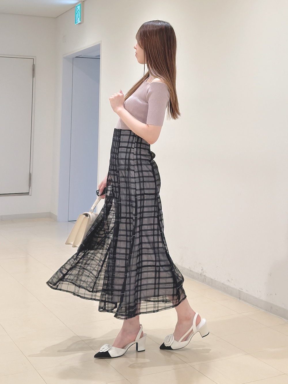 ベージュ系のニット/セーター、ブルー系のスカート、ホワイト系のハンドバッグを着用したレディースの春コーディネートの4枚目の写真