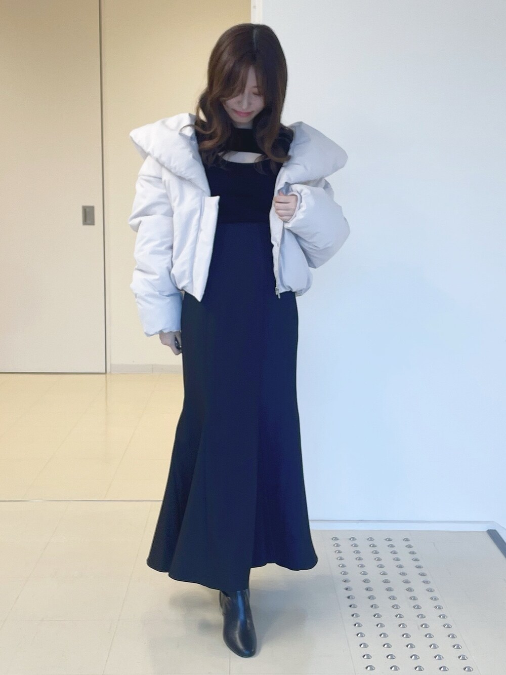 ブラック系のニット/セーター、ピンク系のダウンジャケット/コート、ブラック系のスカートを着用したレディースの冬コーディネートの2枚目の写真