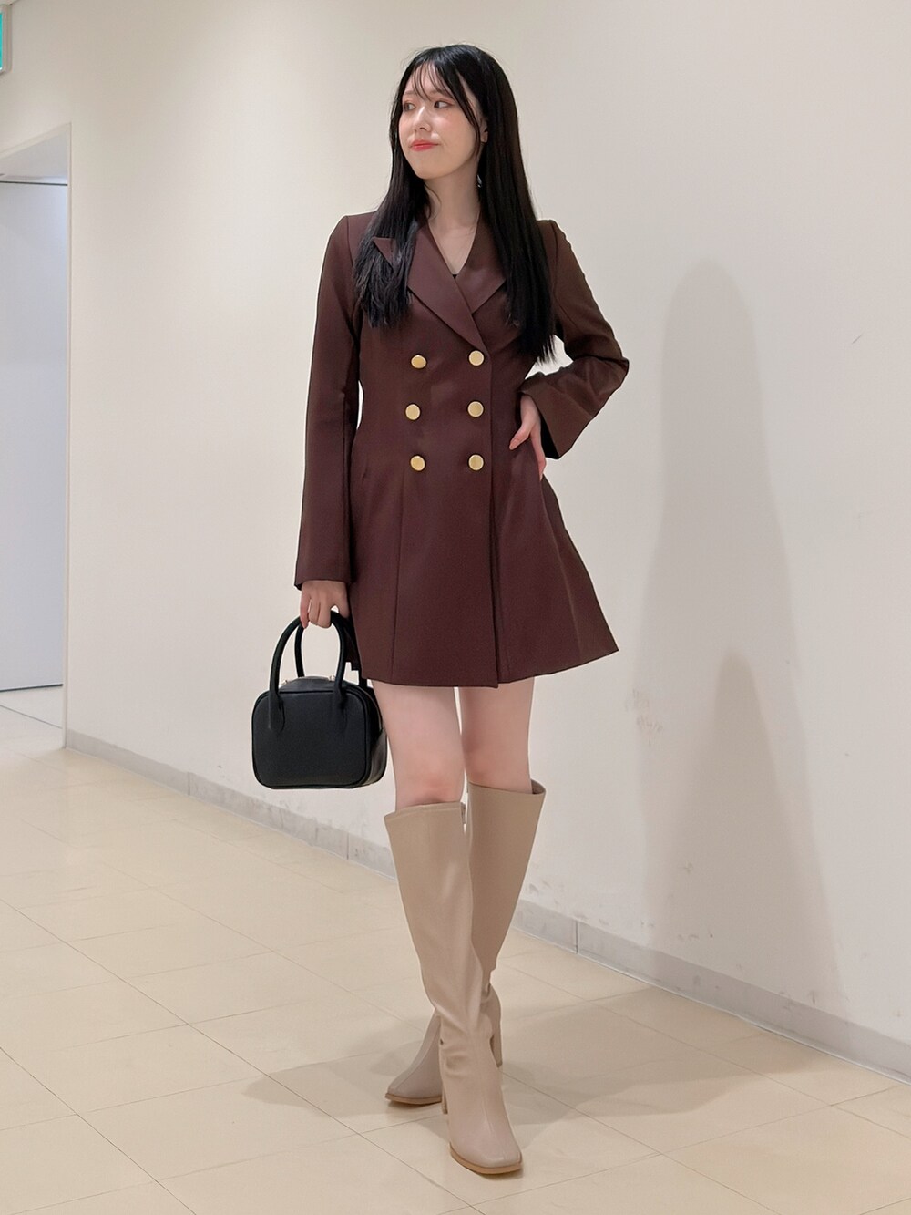 ベージュ系のブーツ、ブラウン系のワンピース、ブラック系のハンドバッグを着用したレディースの夏コーディネートの4枚目の写真