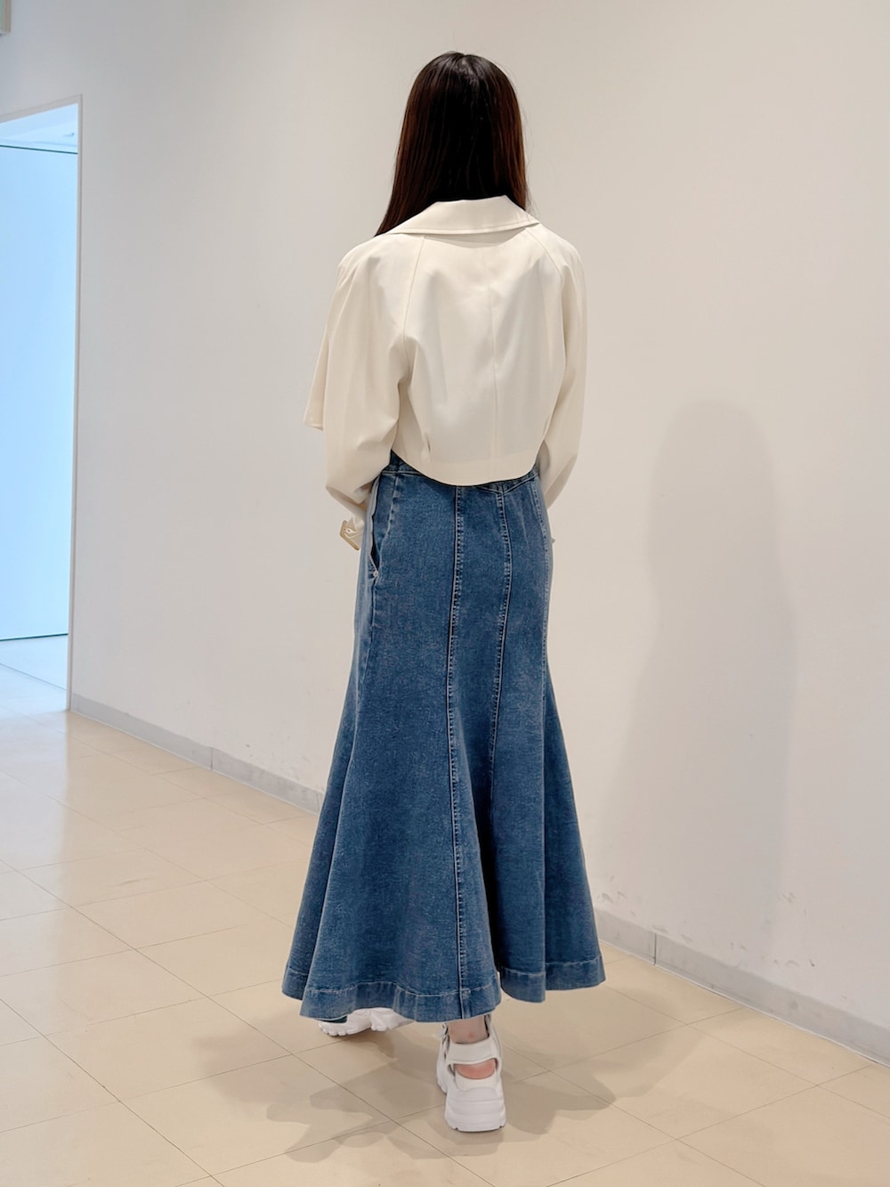 ホワイト系のトレンチコート、ブルー系のスカート、ホワイト系のサンダルを着用したレディースの春コーディネートの4枚目の写真