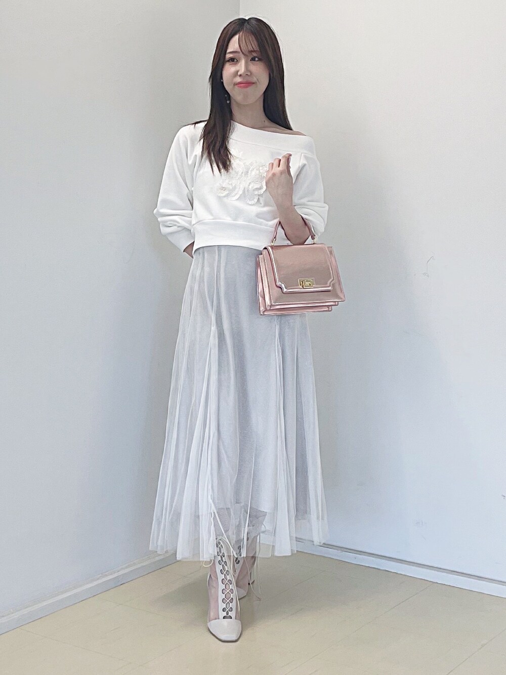 ホワイト系のスウェット、ホワイト系のスカート、ピンク系のハンドバッグを着用したレディースの秋コーディネートの2枚目の写真