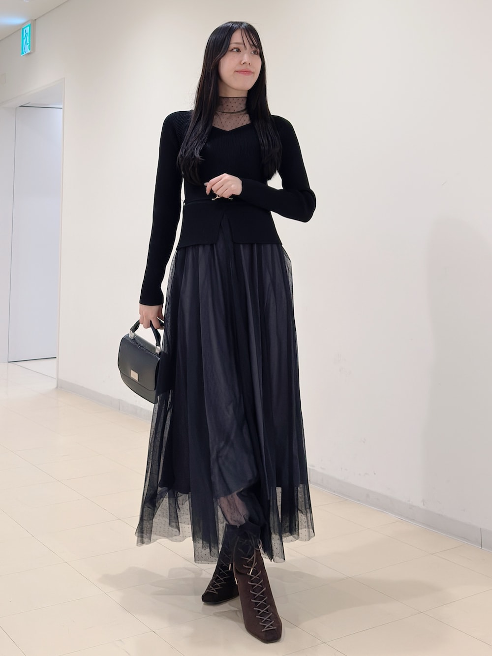 ブラック系のワンピース、ブラック系のハンドバッグ、ブラウン系のブーツを着用したレディースの秋コーディネートの3枚目の写真