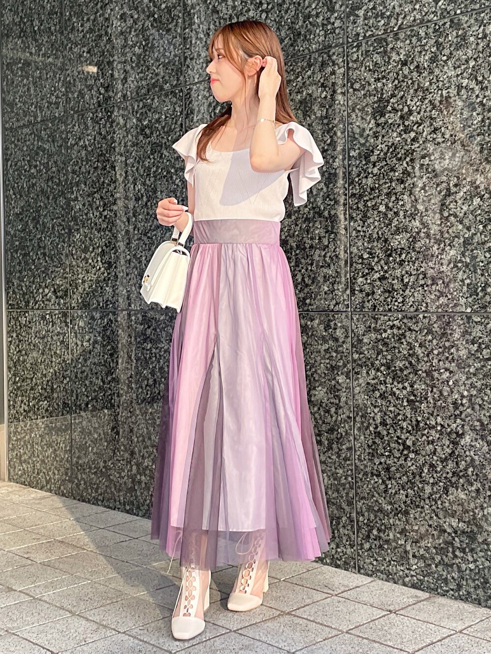 ピンク系のニット/セーター、ホワイト系のハンドバッグ、ホワイト系のブーツを着用したレディースの夏コーディネートの3枚目の写真