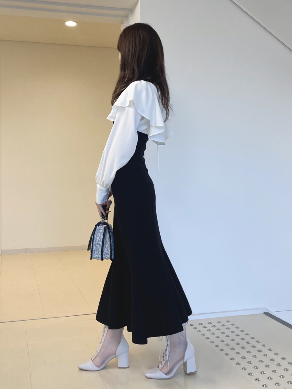 ホワイト系のブーツ、ブラック系のショルダーバッグ、ブラック系のワンピースを着用したレディースの秋コーディネートの4枚目の写真