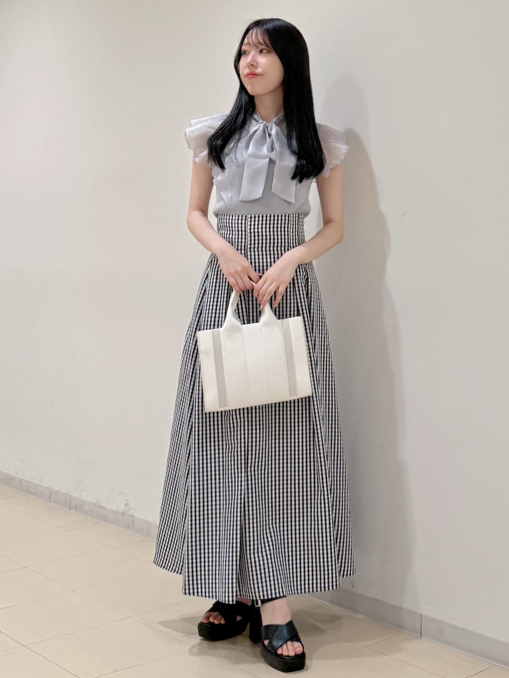 グレー系のニット/セーター、その他のスカート、ホワイト系のトートバッグを着用したレディースの春コーディネートの2枚目の写真