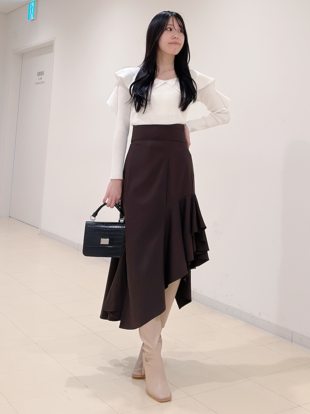 ホワイト系のニット/セーター、ブラウン系のスカート、ブラック系のハンドバッグを着用したレディースの秋コーディネートの5枚目の写真
