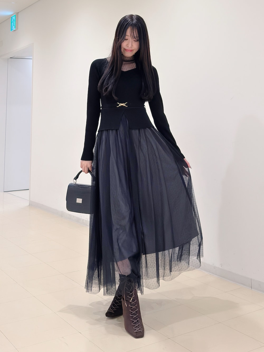 ブラック系のワンピース、ブラック系のハンドバッグ、ブラウン系のブーツを着用したレディースの秋コーディネートの2枚目の写真