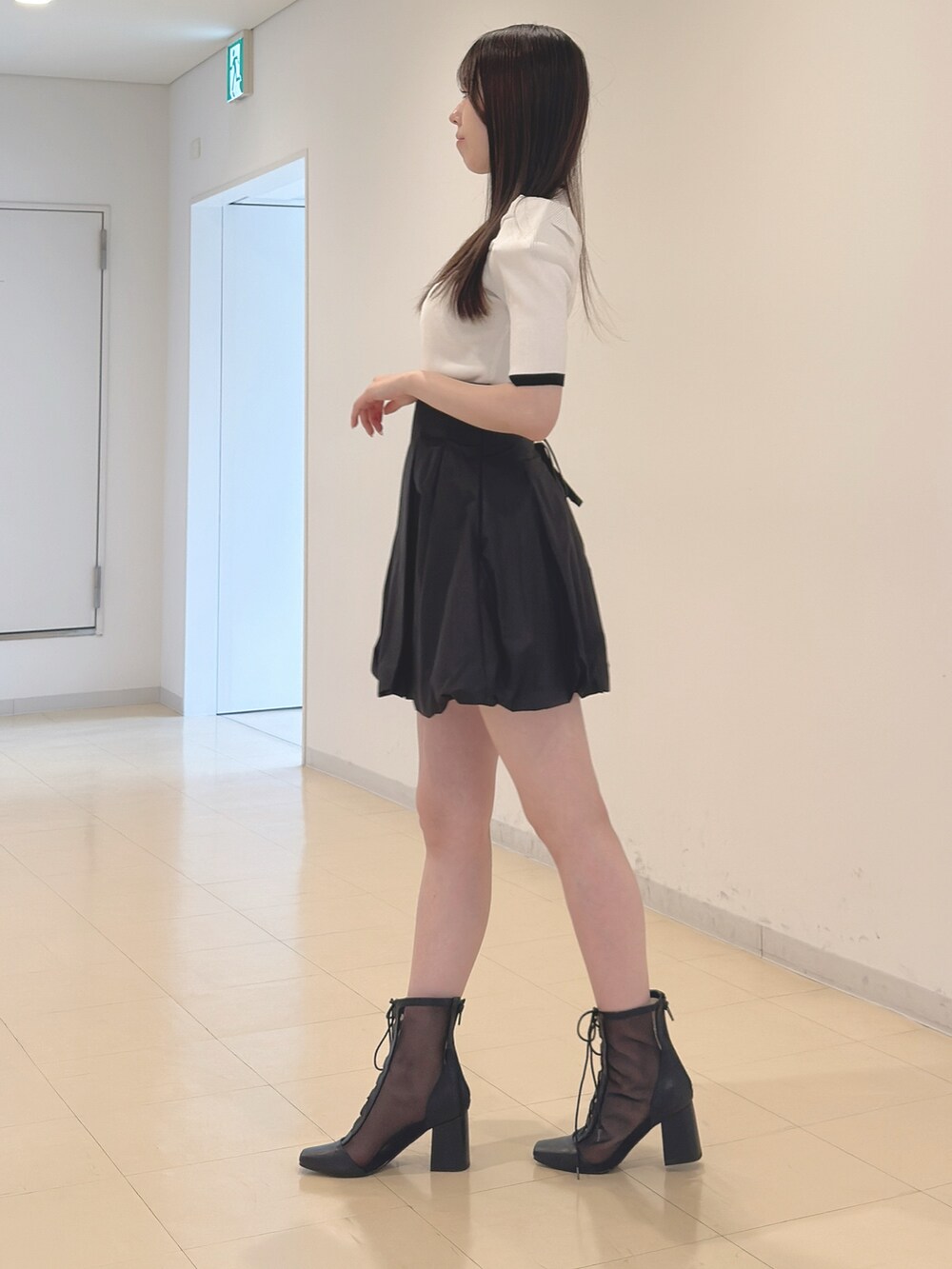 ホワイト系のニット/セーター、ブラック系のスカート、ブラック系のブーツを着用したレディースの春コーディネートの4枚目の写真