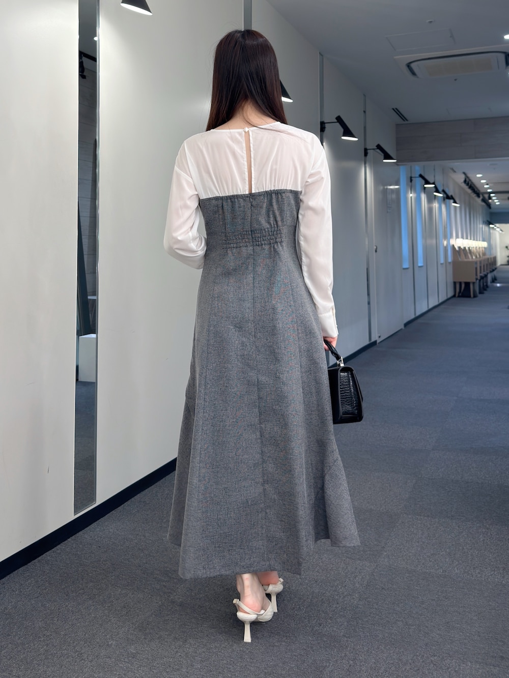 ブラック系のワンピース、ブラック系のハンドバッグ、ホワイト系のパンプスを着用したレディースの春コーディネートの4枚目の写真