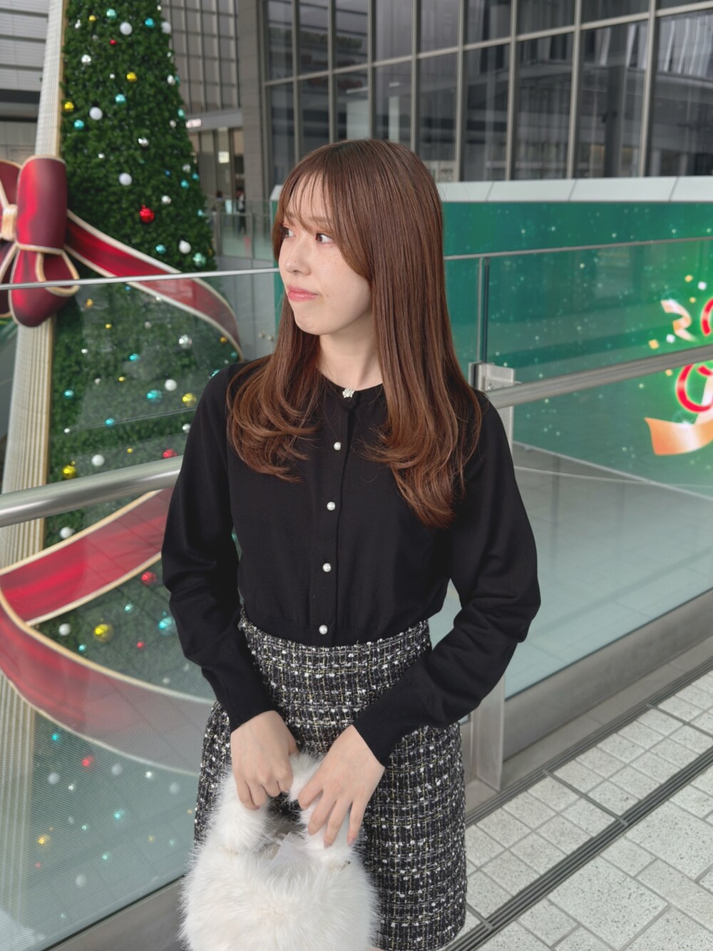 ブラック系のカーディガン/ボレロ、ブラック系のスカート、ホワイト系のハンドバッグを着用したレディースの秋コーディネートの7枚目の写真