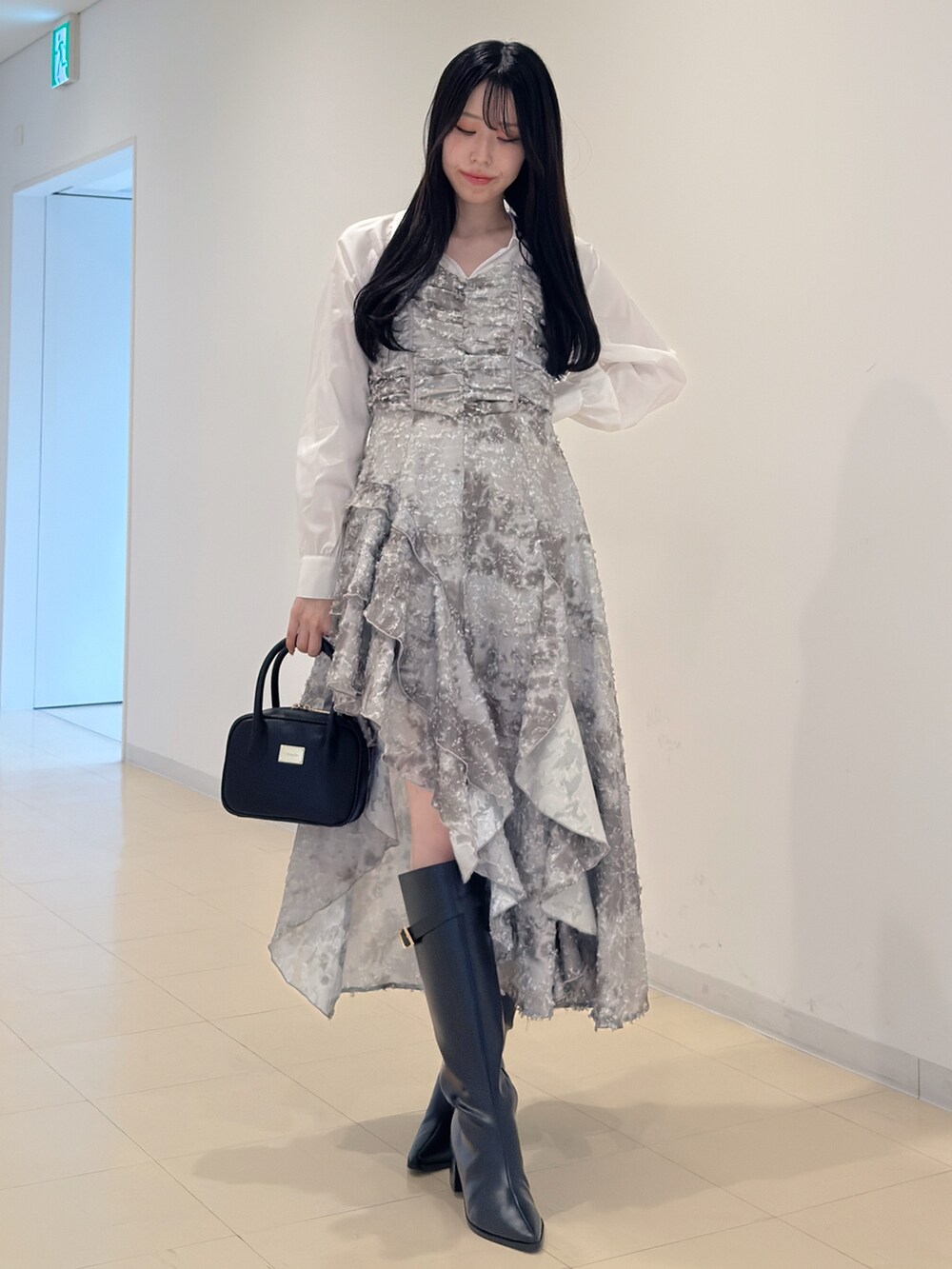 グリーン系のワンピース、ブラック系のハンドバッグ、ブラック系のブーツを着用したレディースの秋コーディネートの2枚目の写真