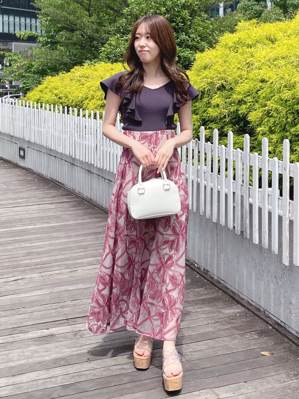 レッド系のスカート、グレー系のニット/セーター、ホワイト系のボストンバッグを着用したレディースの春コーディネートの2枚目の写真