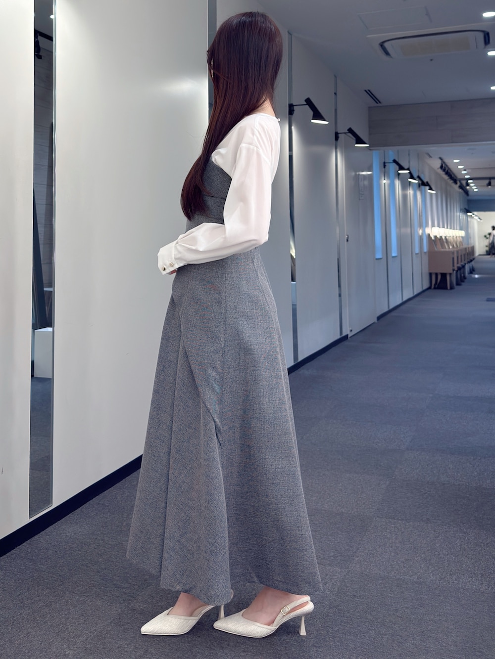 ブラック系のワンピース、ブラック系のハンドバッグ、ホワイト系のパンプスを着用したレディースの春コーディネートの3枚目の写真