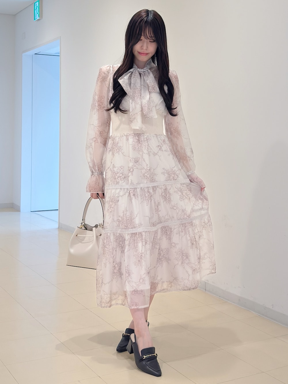 ベージュ系のワンピース、ホワイト系のショルダーバッグ、ブラウン系のパンプスを着用したレディースの冬コーディネートの2枚目の写真