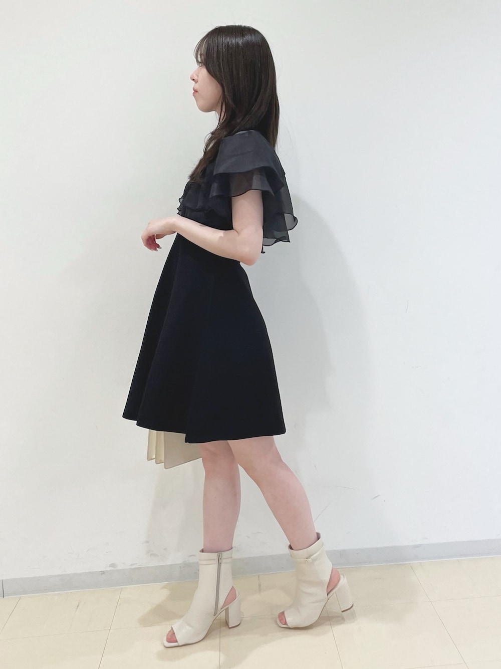 ブラック系のワンピース、ホワイト系のハンドバッグ、ホワイト系のブーツを着用したレディースの春コーディネートの5枚目の写真