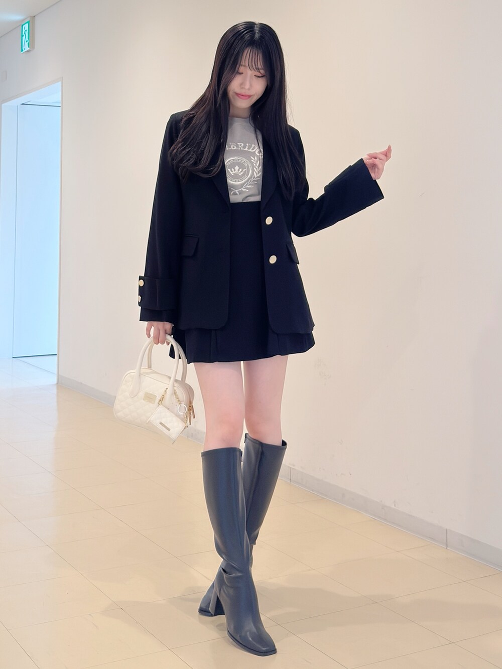 ブラック系のテーラードジャケット、グレー系のニット/セーター、ブラック系のスカートを着用したレディースの秋コーディネートの5枚目の写真