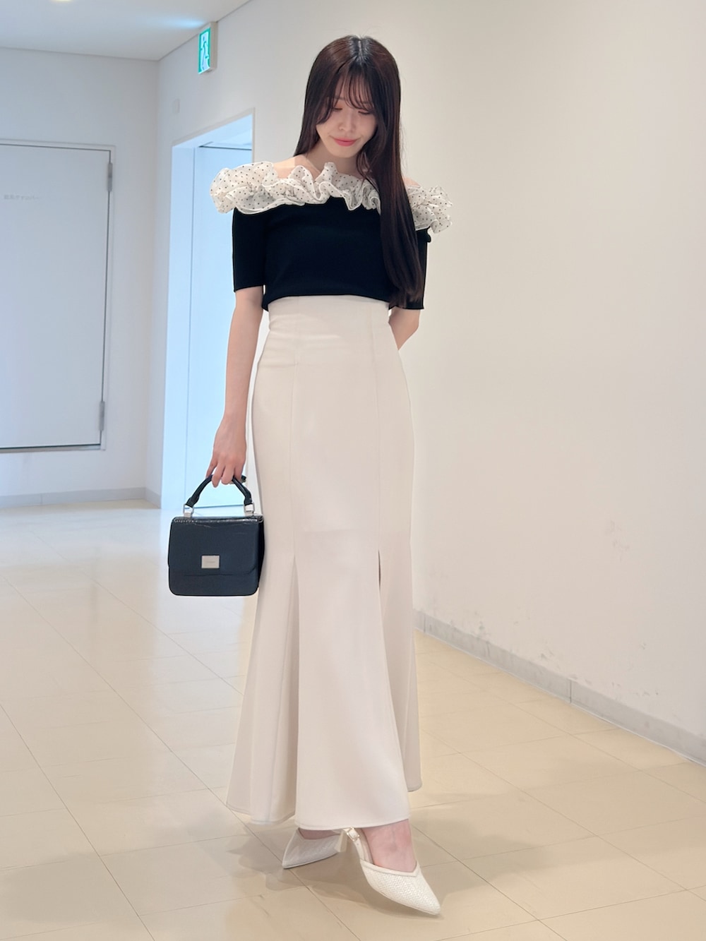 その他のニット/セーター、ホワイト系のスカート、ブラック系のハンドバッグを着用したレディースの春コーディネートの2枚目の写真