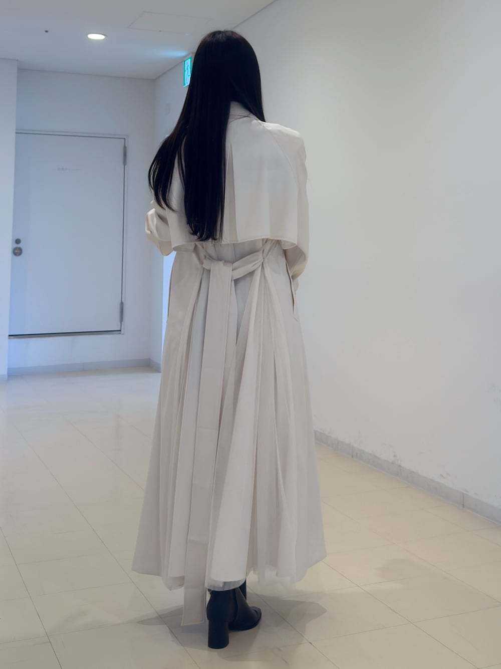 ホワイト系のトレンチコート、その他のニット/セーター、グレー系のスカートを着用したレディースの冬コーディネートの4枚目の写真