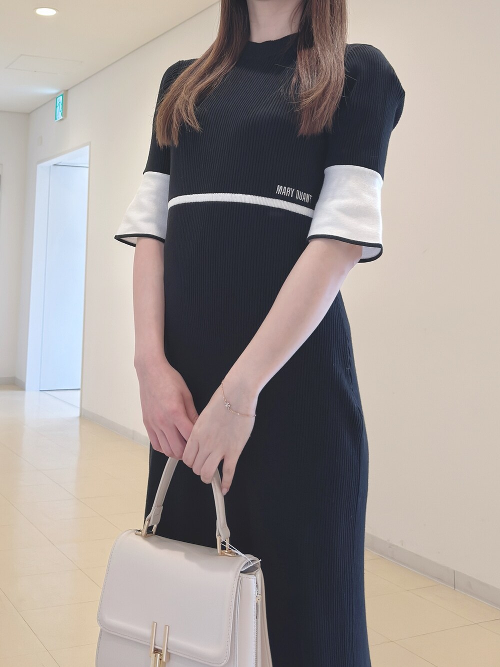 ブラック系のワンピース、ホワイト系のハンドバッグ、ブラック系のブーツを着用したレディースの春コーディネートの6枚目の写真