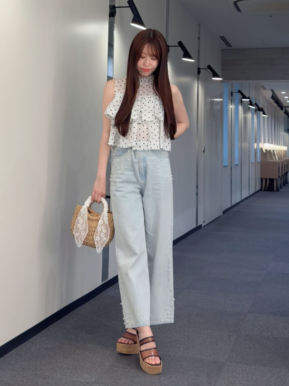 ベージュ系のハンドバッグ、ブラウン系のサンダル、ブルー系のデニムパンツを着用したレディースの夏コーディネートの2枚目の写真