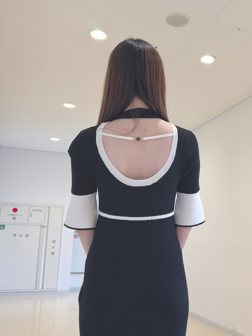 ブラック系のワンピース、ホワイト系のハンドバッグ、ブラック系のブーツを着用したレディースの春コーディネートの7枚目の写真