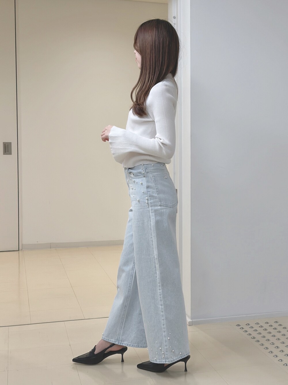 ホワイト系のカーディガン/ボレロ、ブルー系のデニムパンツ、ブラック系のハンドバッグを着用したレディースの冬コーディネートの3枚目の写真