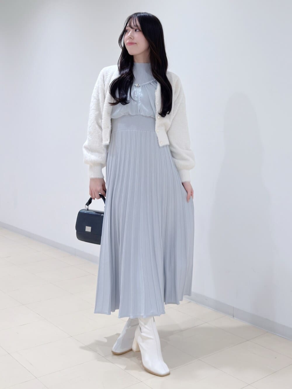 ブラック系のハンドバッグ、ホワイト系のブーツ、ホワイト系のカーディガン/ボレロを着用したレディースの冬コーディネートの2枚目の写真