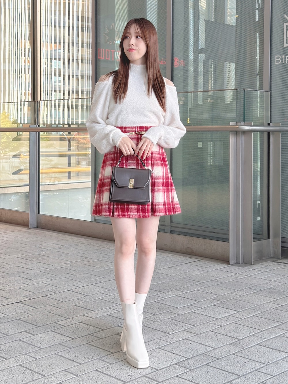 ブラウン系のチェスターコート、ホワイト系のニット/セーター、レッド系のその他パンツを着用したレディースの冬コーディネートの2枚目の写真