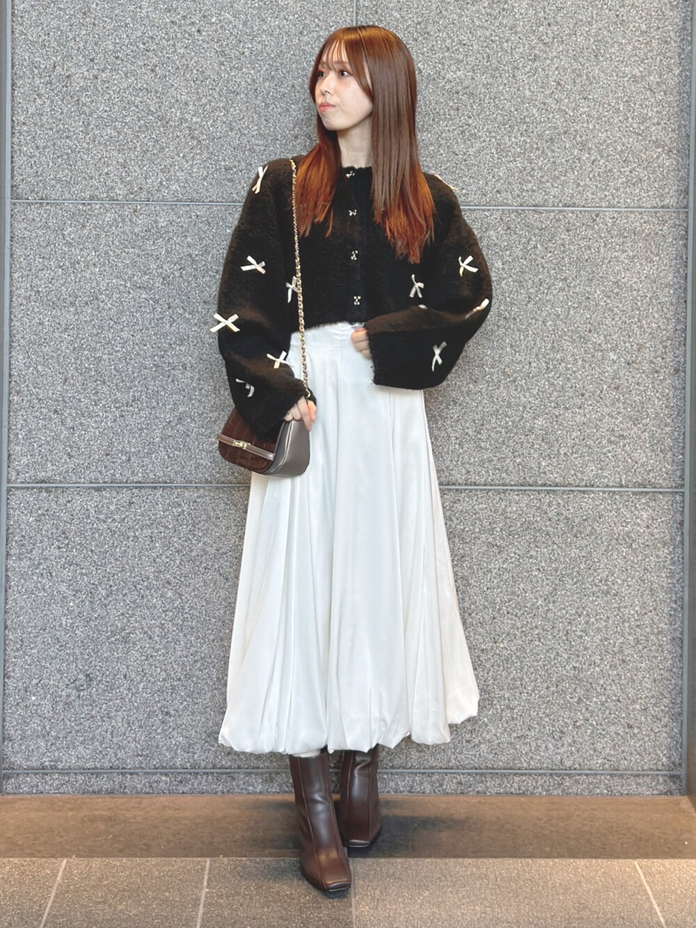 ブラック系のカーディガン/ボレロ、ホワイト系のスカート、ブラウン系のハンドバッグを着用したレディースの秋コーディネートの3枚目の写真