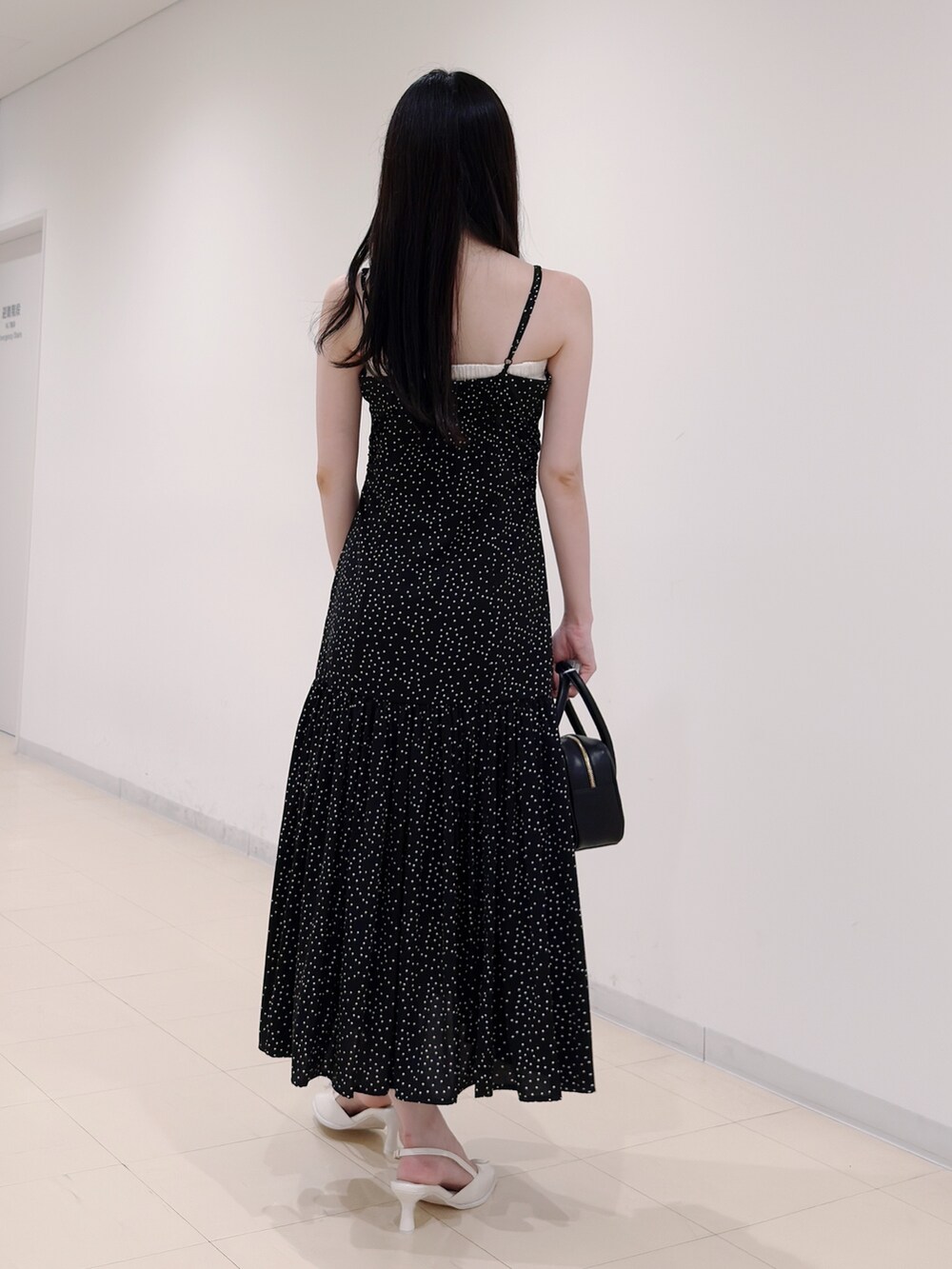 ブラック系のワンピース、ブラック系のハンドバッグ、ホワイト系のパンプスを着用したレディースの秋コーディネートの4枚目の写真