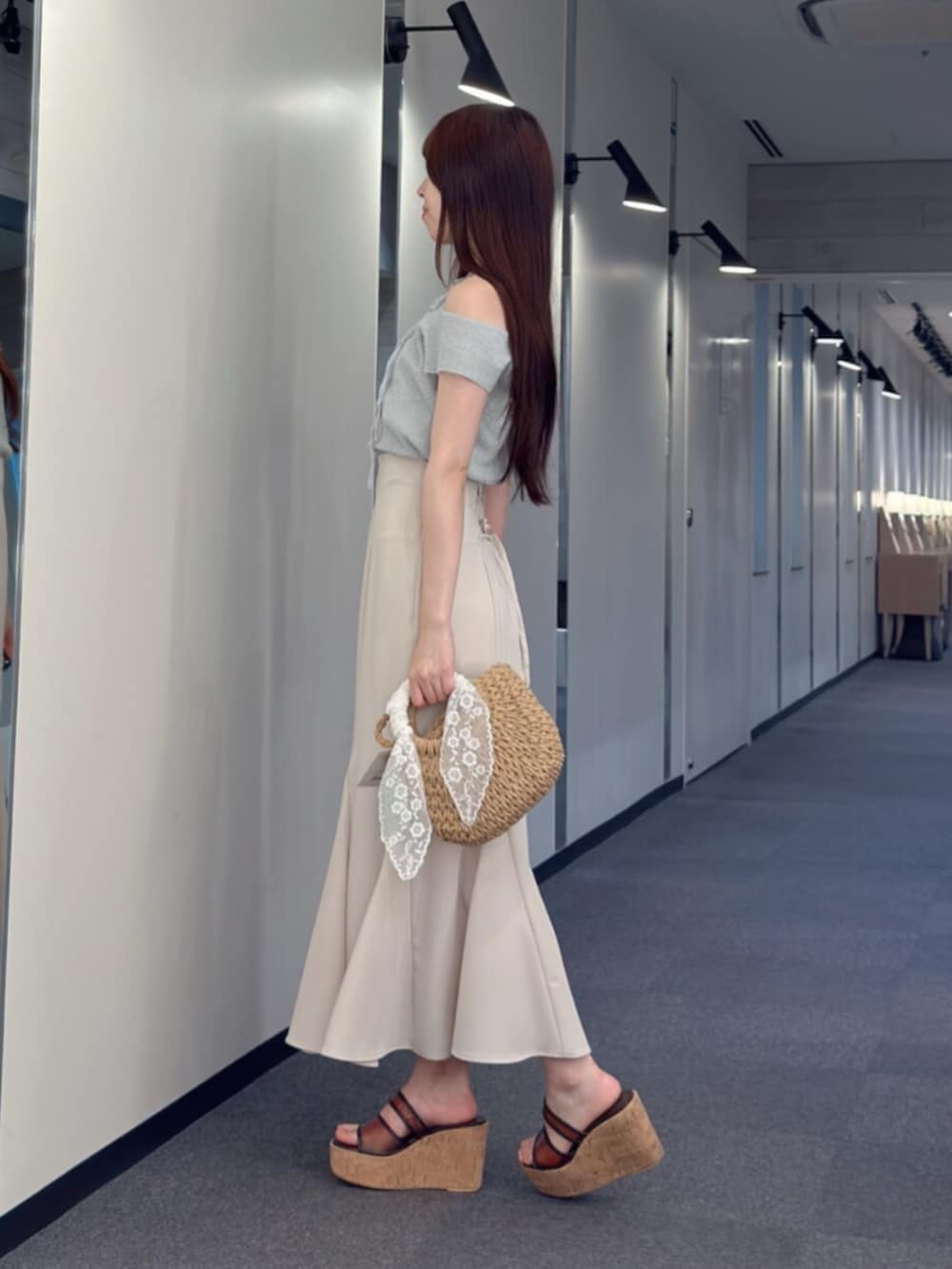ホワイト系のスカート、ベージュ系のハンドバッグ、ブラウン系のサンダルを着用したレディースの夏コーディネートの2枚目の写真