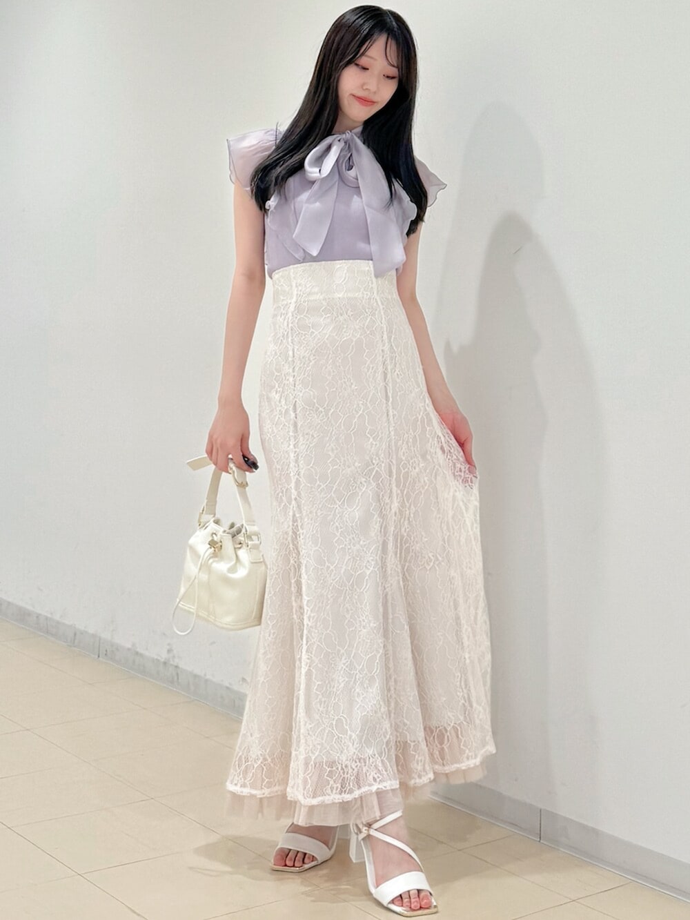 ホワイト系のスカート、ホワイト系のサンダル、ホワイト系のハンドバッグを着用したレディースの春コーディネートの3枚目の写真