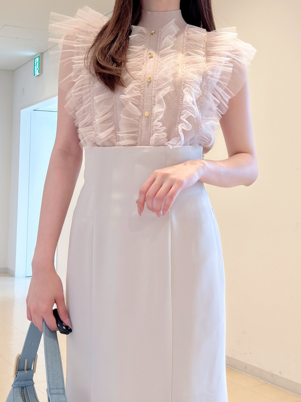 ピンク系のニット/セーター、ホワイト系のスカート、ブルー系のショルダーバッグを着用したレディースの春コーディネートの7枚目の写真