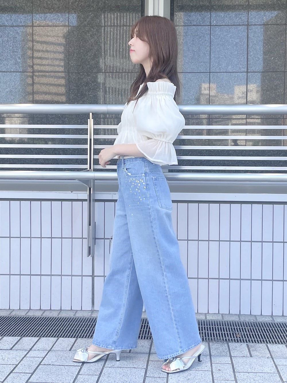 ブルー系のデニムパンツ、シルバー系のハンドバッグ、シルバー系のサンダルを着用したレディースの春コーディネートの4枚目の写真