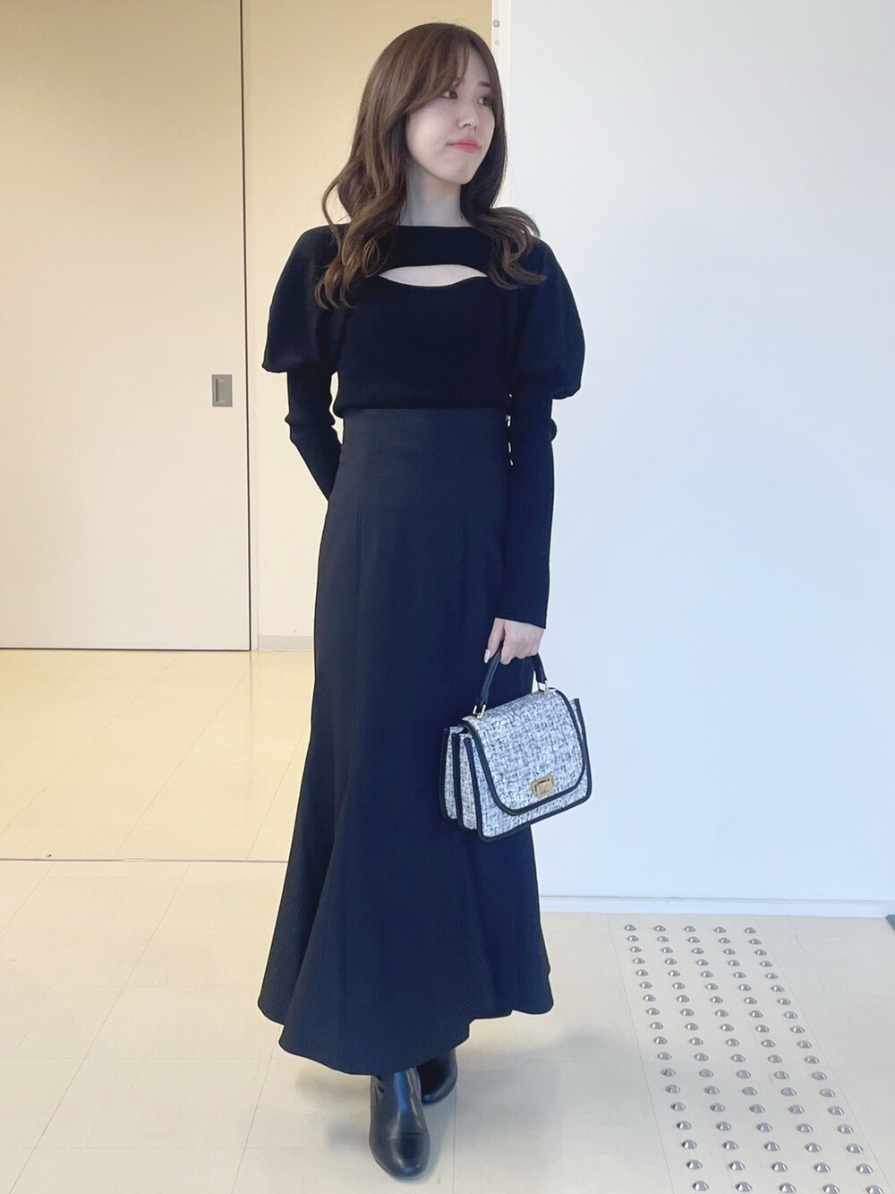 ブラック系のスカート、ブラック系のショルダーバッグ、ブラック系のブーツを着用したレディースの冬コーディネートの3枚目の写真