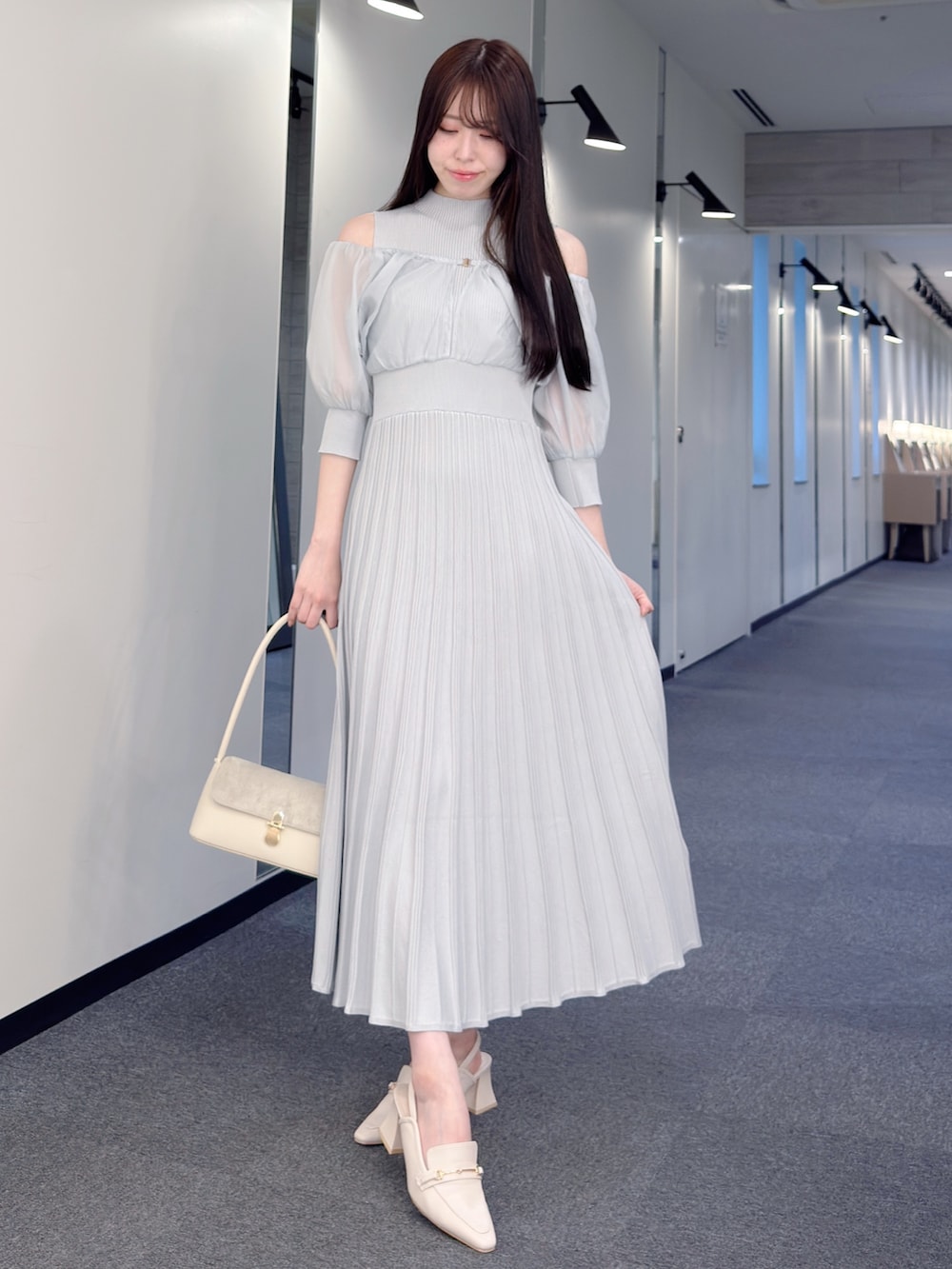 グレー系のワンピース、ホワイト系のハンドバッグ、ホワイト系のパンプスを着用したレディースの春コーディネートの2枚目の写真